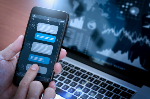 Ecran de smartphone affichant des SMS à côté d'un rapport CRM sur un ordinateur